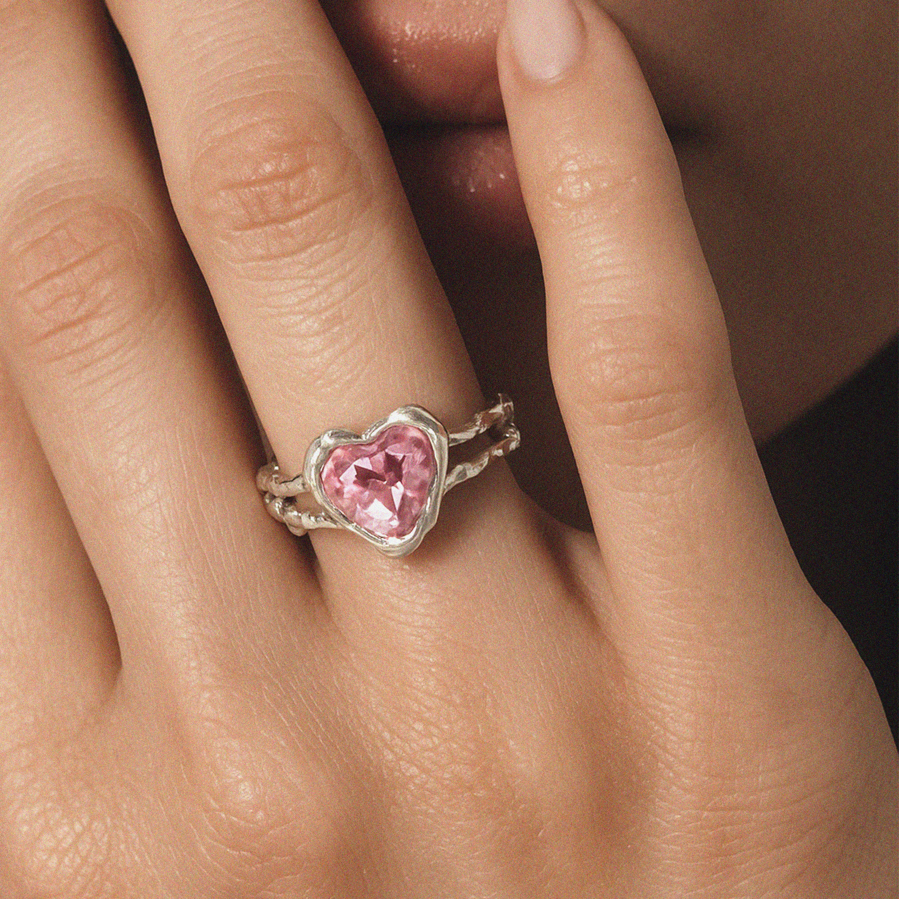 Single silver open-back ring with pink heart-shaped crystal under sunlight