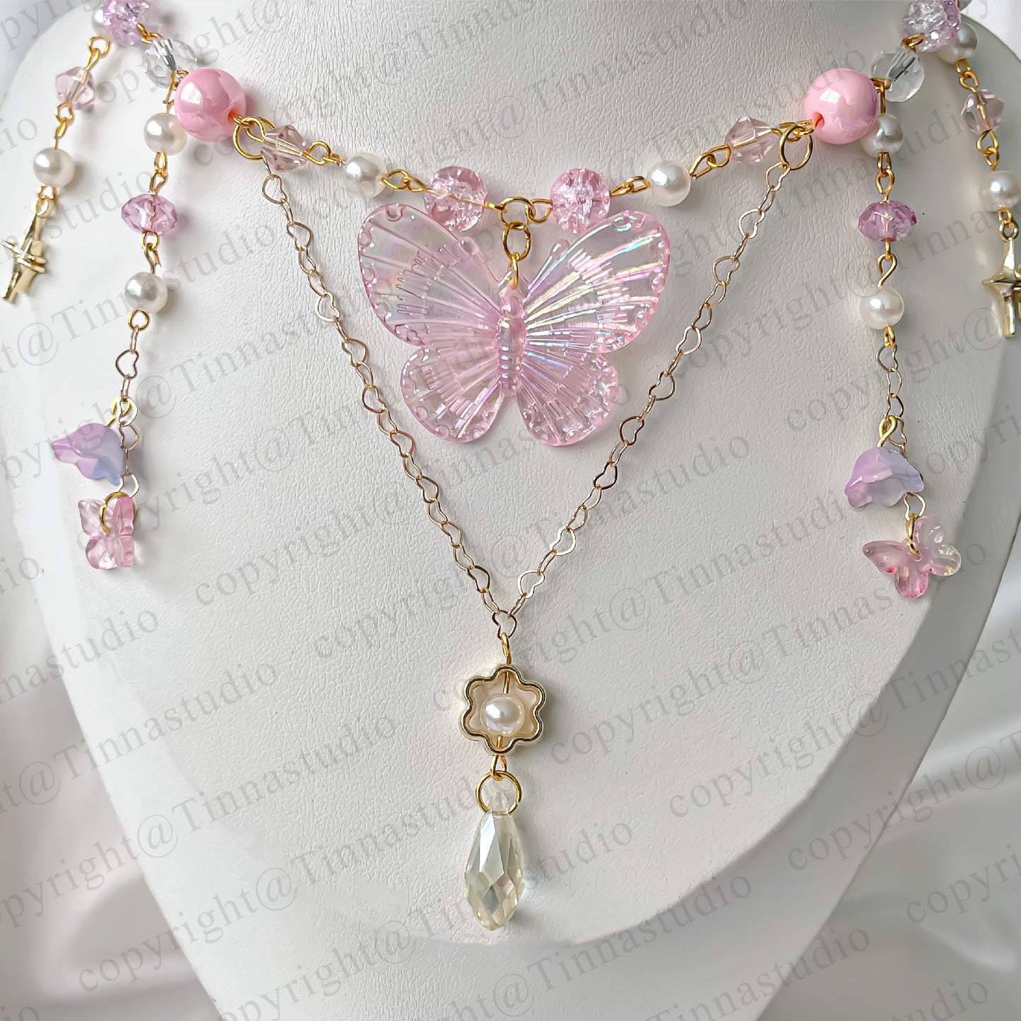 Close-up of pink fairycore necklace featuring iridescent butterfly and gold-plated chains.