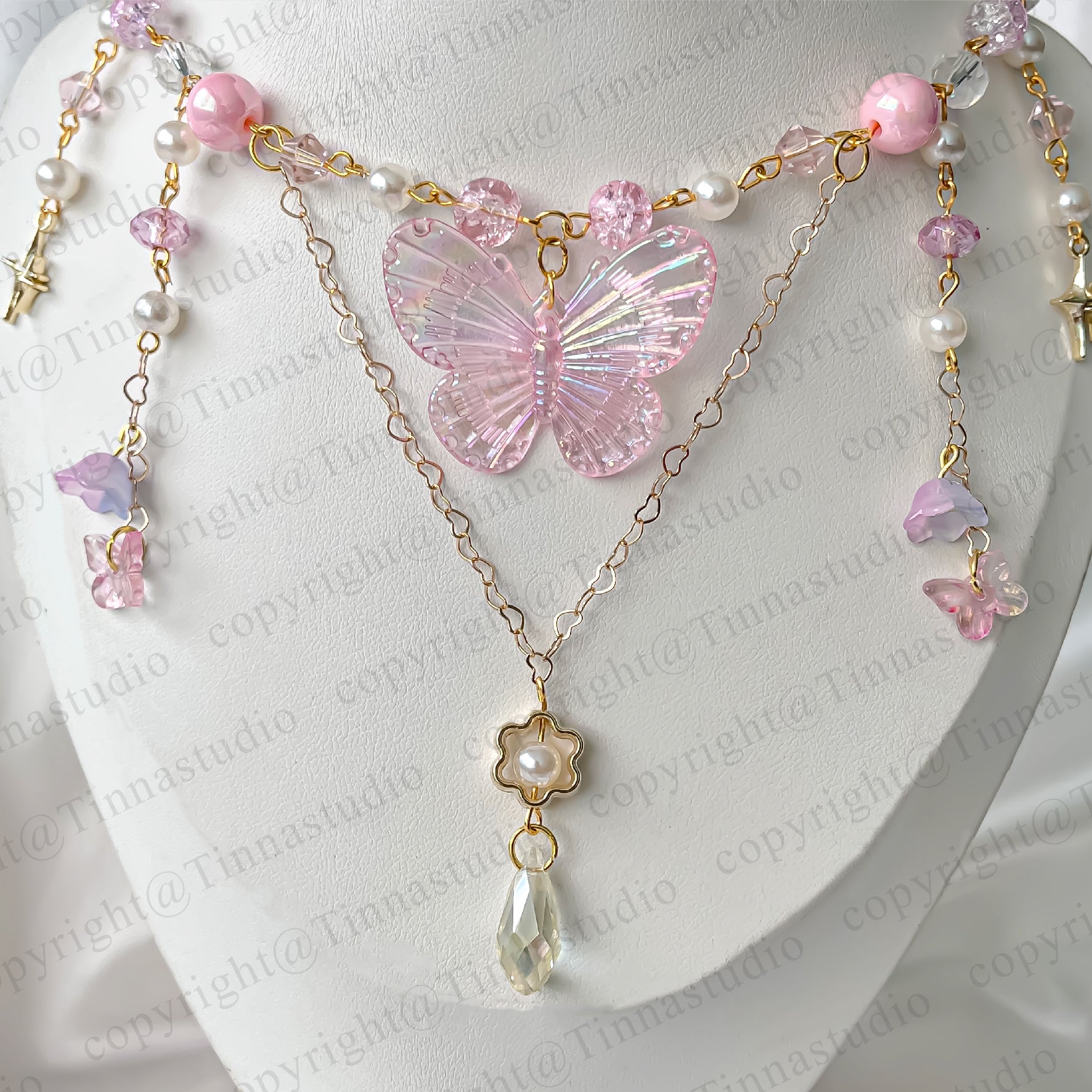 Close-up of pink fairycore necklace featuring iridescent butterfly and gold-plated chains.